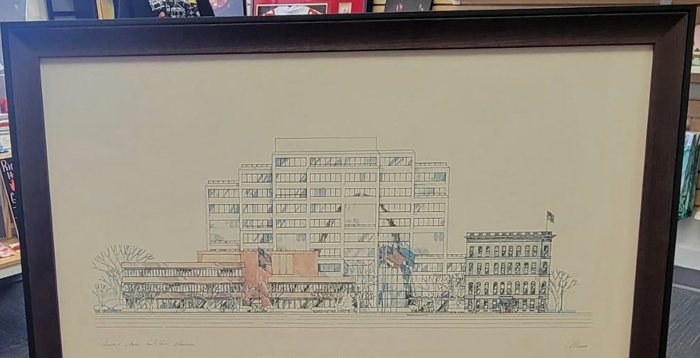 Close crop of an architectural line drawing of a city block, in a cream mat inside a dark walnut toned frame.
